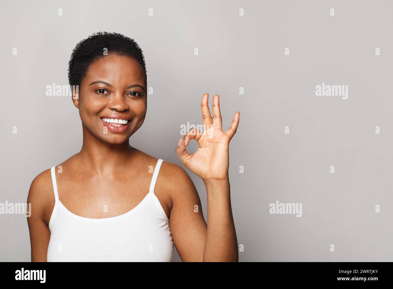 Donna bruna felice che mostra un buon gesto su sfondo bianco Foto Stock