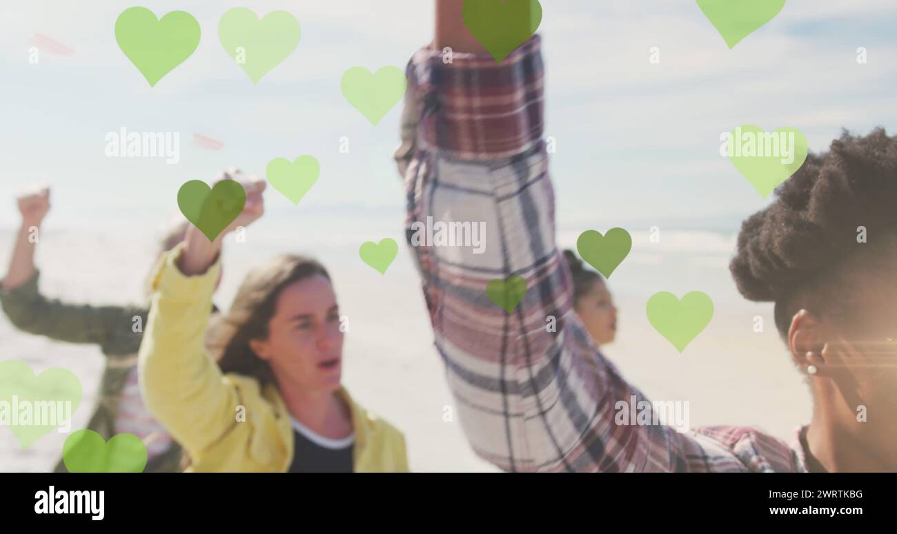 Immagine di cuori verdi su diverse persone che si alzano a pugni Foto Stock