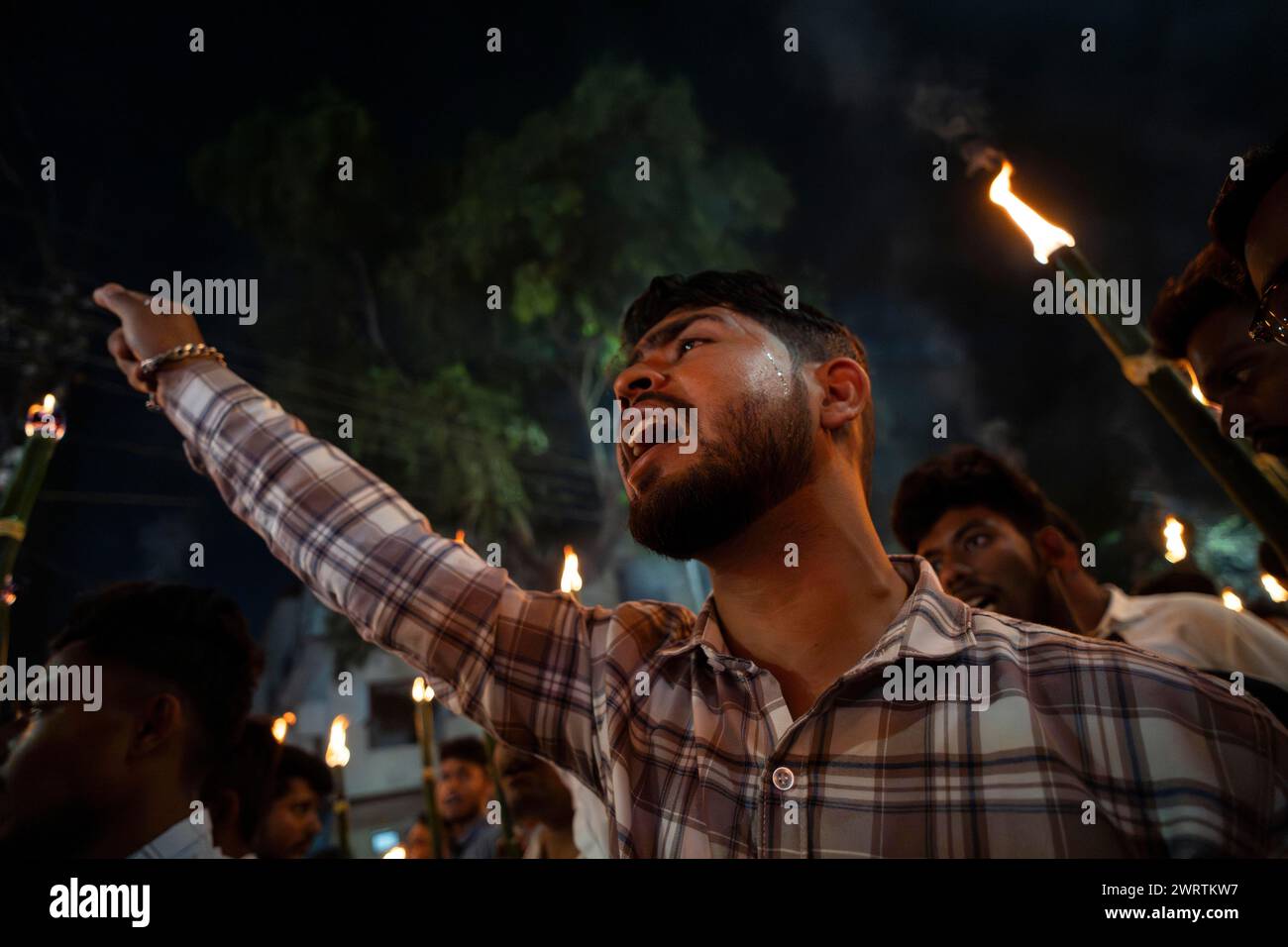 I membri dell'All Assam Students' Union (AASU) prendono parte a una manifestazione fiammeggiante di torce e gridano slogan per protestare contro l'attuazione del Foto Stock