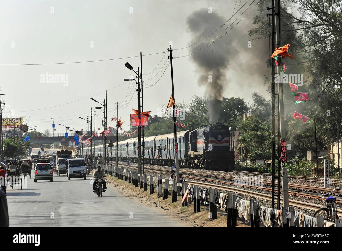 Treno che viaggia accanto a una strada con veicoli, fumogeno, confine India-Nepal, Gorakhpur, Bhairahawa, India, Nepal Foto Stock
