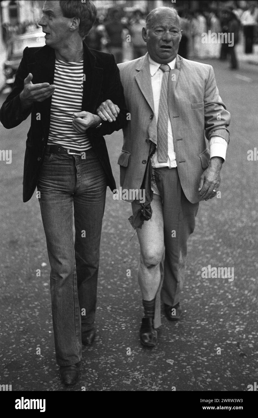 Crimine d'odio Gay Bashing Regno Unito anni '1970 Comportamento omofobo. Rivolte del Carnevale di Notting Hill. Una coppia gay distratta; l'uomo più anziano è stato attaccato e derubato il suo portafoglio è stato rubato. Gay Bashing o Queer Rolling erano termini usati nel momento in cui gli uomini gay erano spesso visti come un bersaglio facile da parte dei giovani omofobi che si erano messi in procinto di ucciderli e derubarli. 29 agosto giorni festivi lunedì 1977. Notting Hill, Londra, Inghilterra, HOMER SYKES Foto Stock