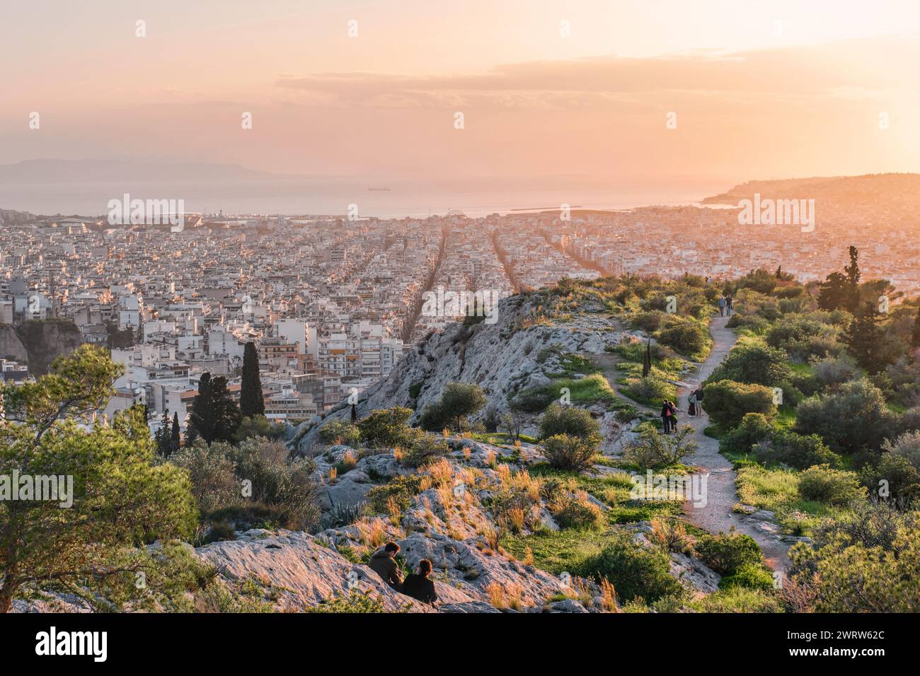 Atene, Grecia - 2 marzo 2024: Paesaggio urbano e mare di Atene al tramonto dalla collina di Filopappo Foto Stock