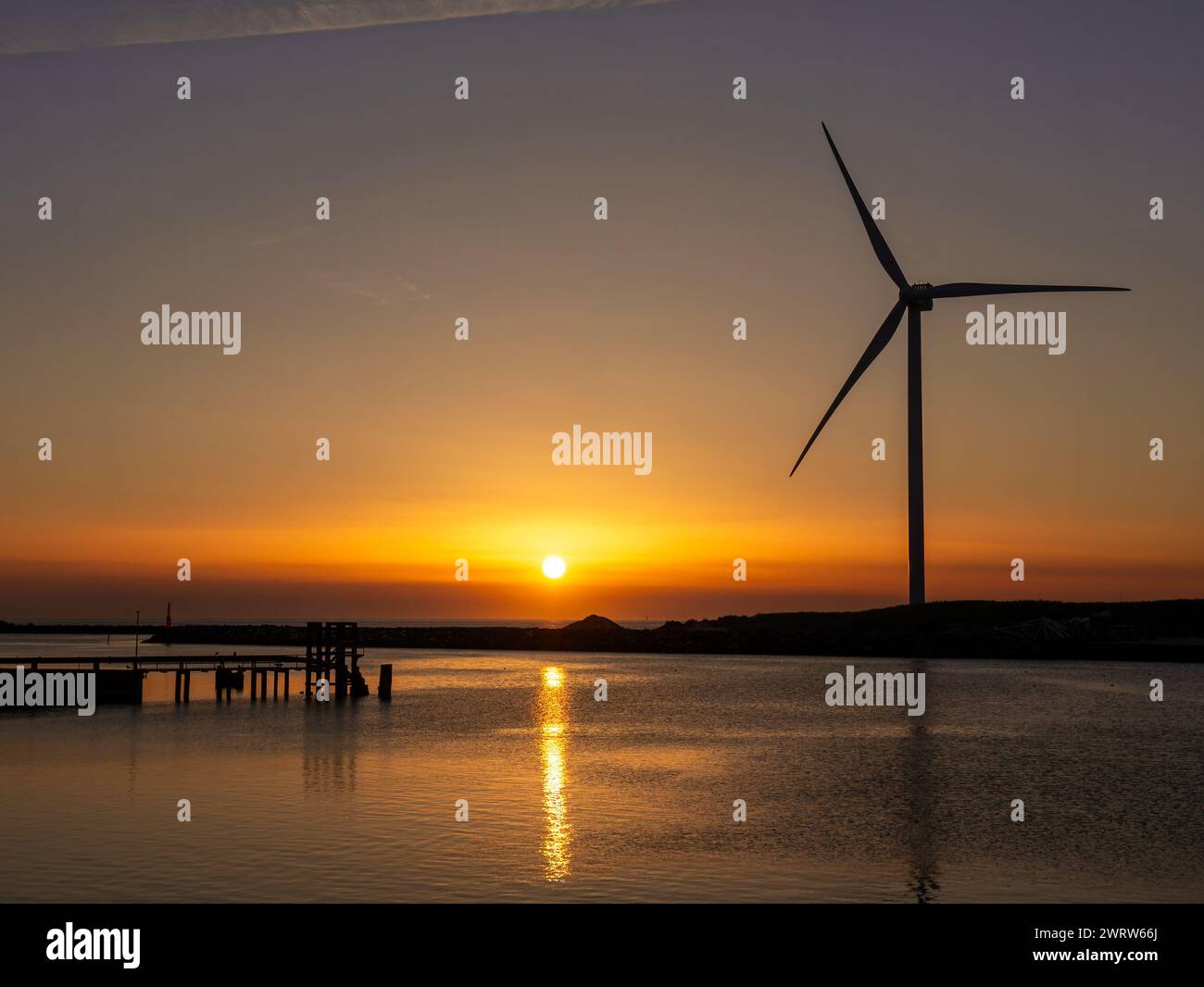 Canale di Hvide Sande con generatore eolico e molo al tramonto sul Mare del Nord, Jutland centrale, Danimarca Foto Stock