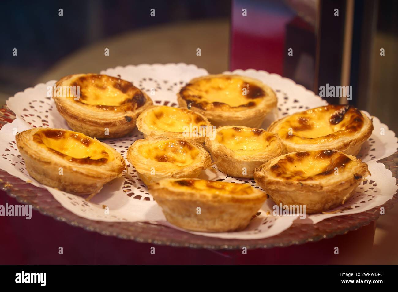 Pasticceria assortita di pastello De nata elegantemente esposta su un pizzo Doily Foto Stock