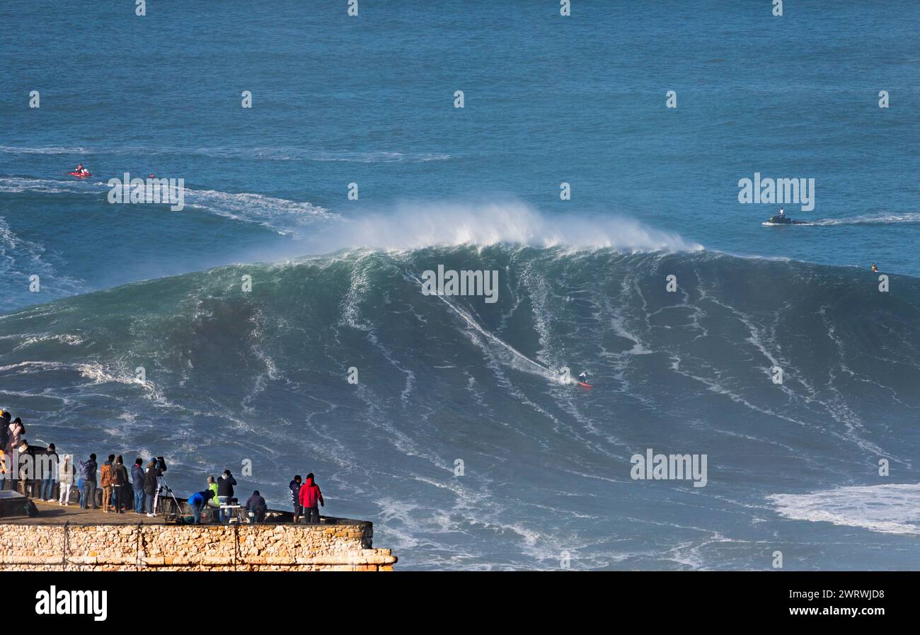 Europa, Portogallo, Regione di Oeste, Nazaré, Surfer e supporto Jet ski cavalcando onde enormi vicino Praia do Norte durante il Free Surfing Event 2022 Foto Stock