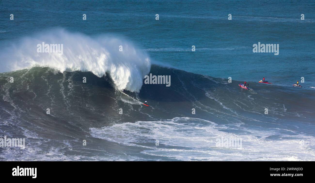 Europa, Portogallo, Regione di Oeste, Nazaré, Surfer e supporto Jet ski cavalcando onde enormi vicino Praia do Norte durante il Free Surfing Event 2022 Foto Stock