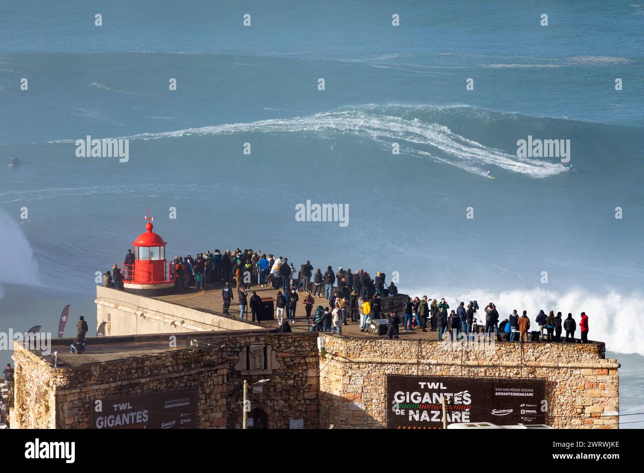 Portogallo, regione di Oeste, Nazaré, Surfer e Jet Ski di supporto in sella a enormi onde vicino a Praia do Norte durante l'evento Free Surfing del gennaio 2022 Foto Stock
