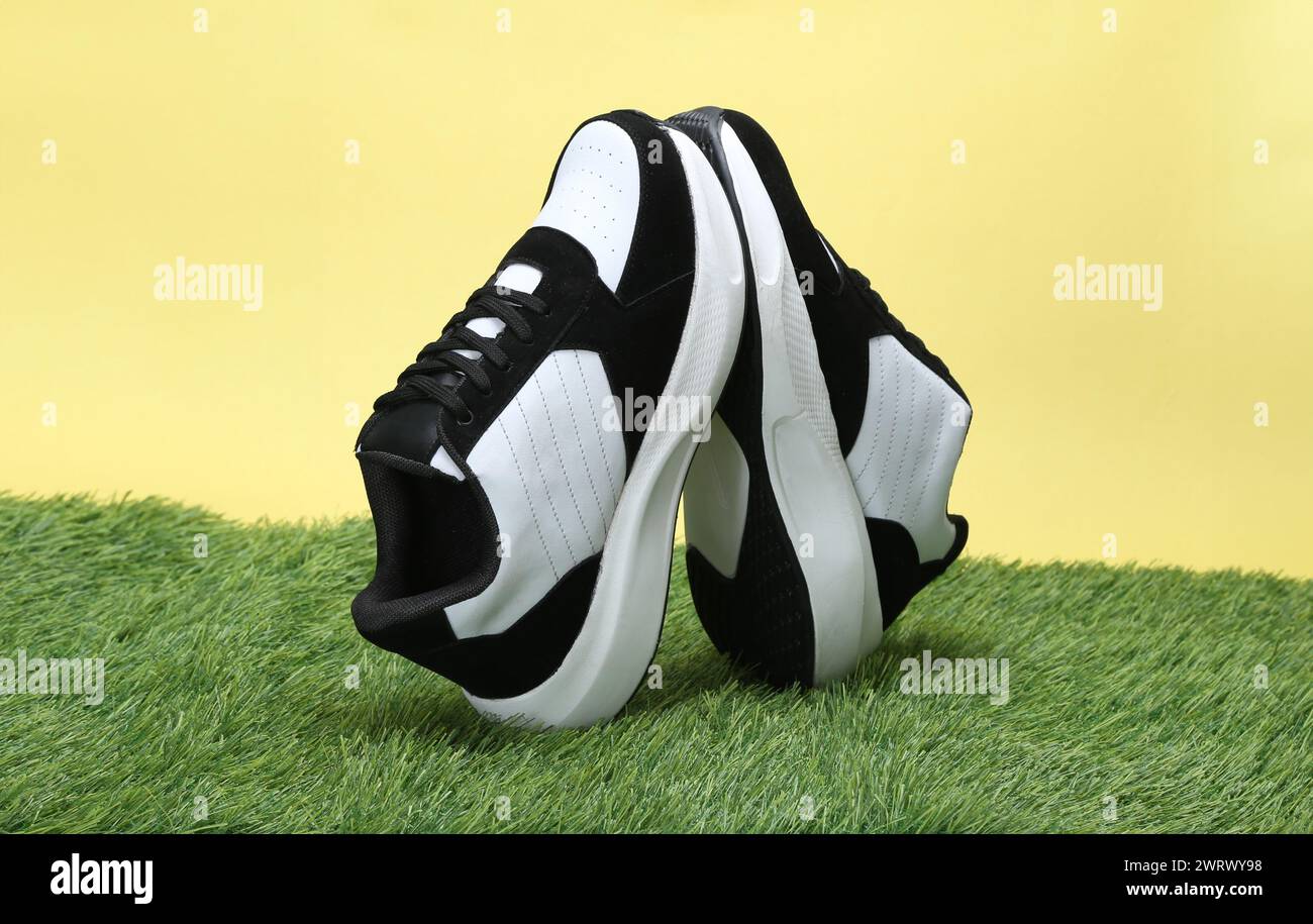 scarpe casual creative scattate su sfondo giallo con erba Foto Stock