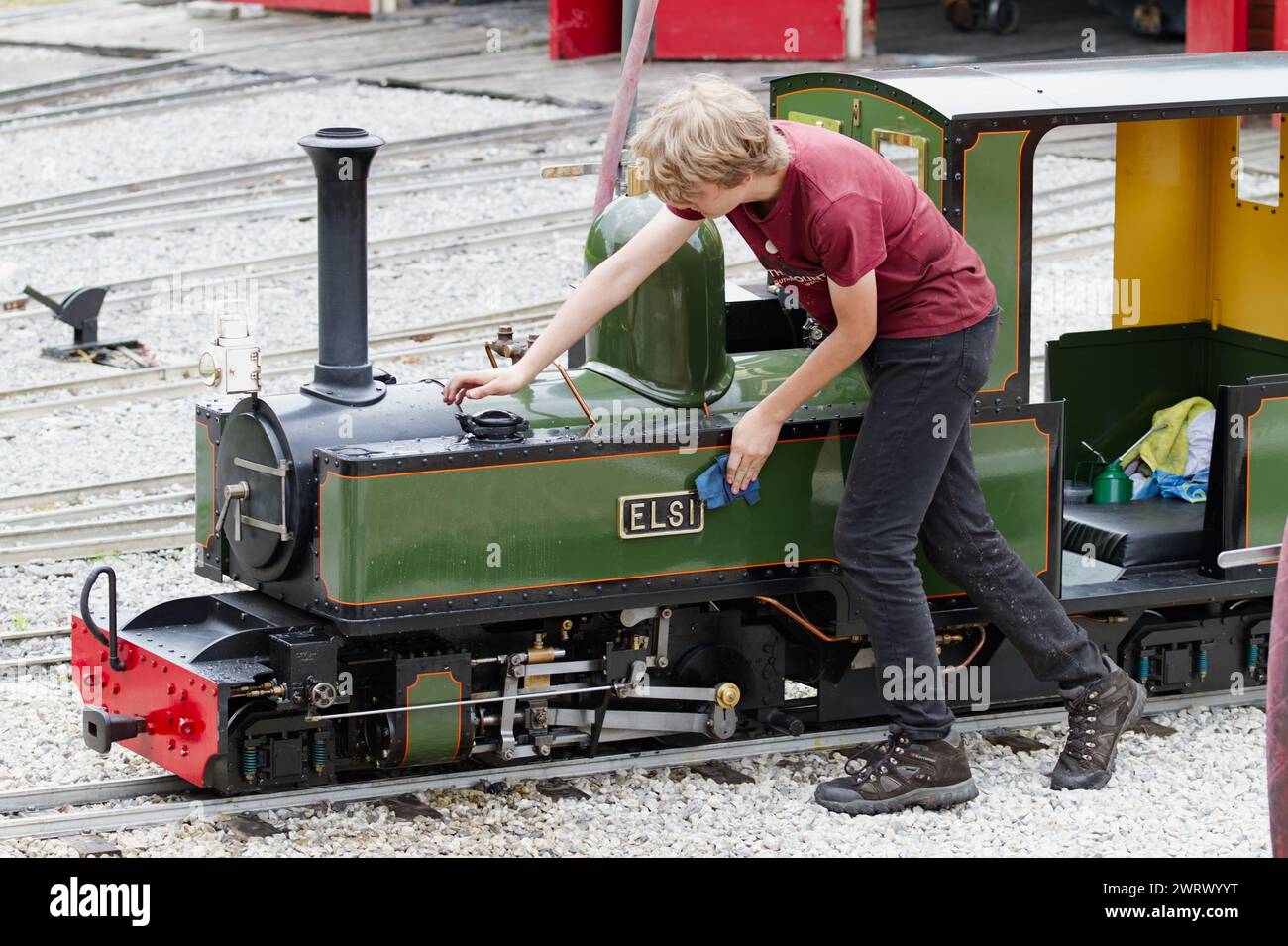 Uomo, lavoratore, pulizia Di Una miniatura in piedi, piccola locomotiva a vapore a scartamento ridotto da 1/4 pollici presso la Moors Valley Railway, Moors Valley UK Foto Stock