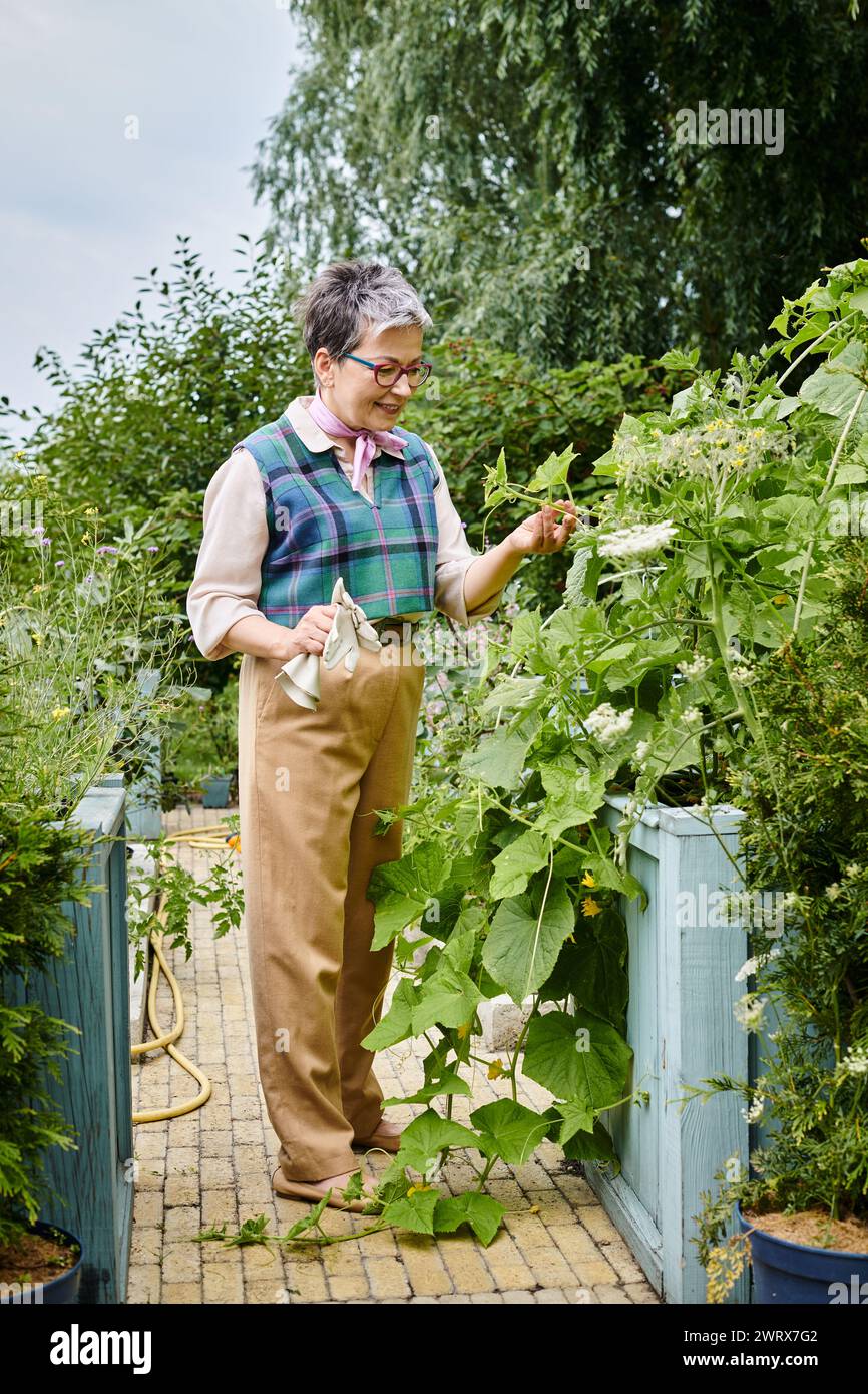 donna matura e sofisticata con capelli corti e un abbigliamento elegante e vivace che si prende cura delle sue piante Foto Stock