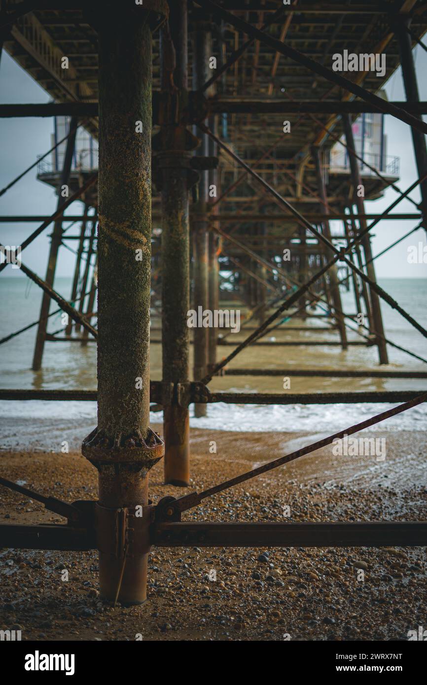 Eastbourne Pier, sulla costa meridionale del Regno Unito. mostra la vecchia architettura arrugginita con le onde. Foto Stock