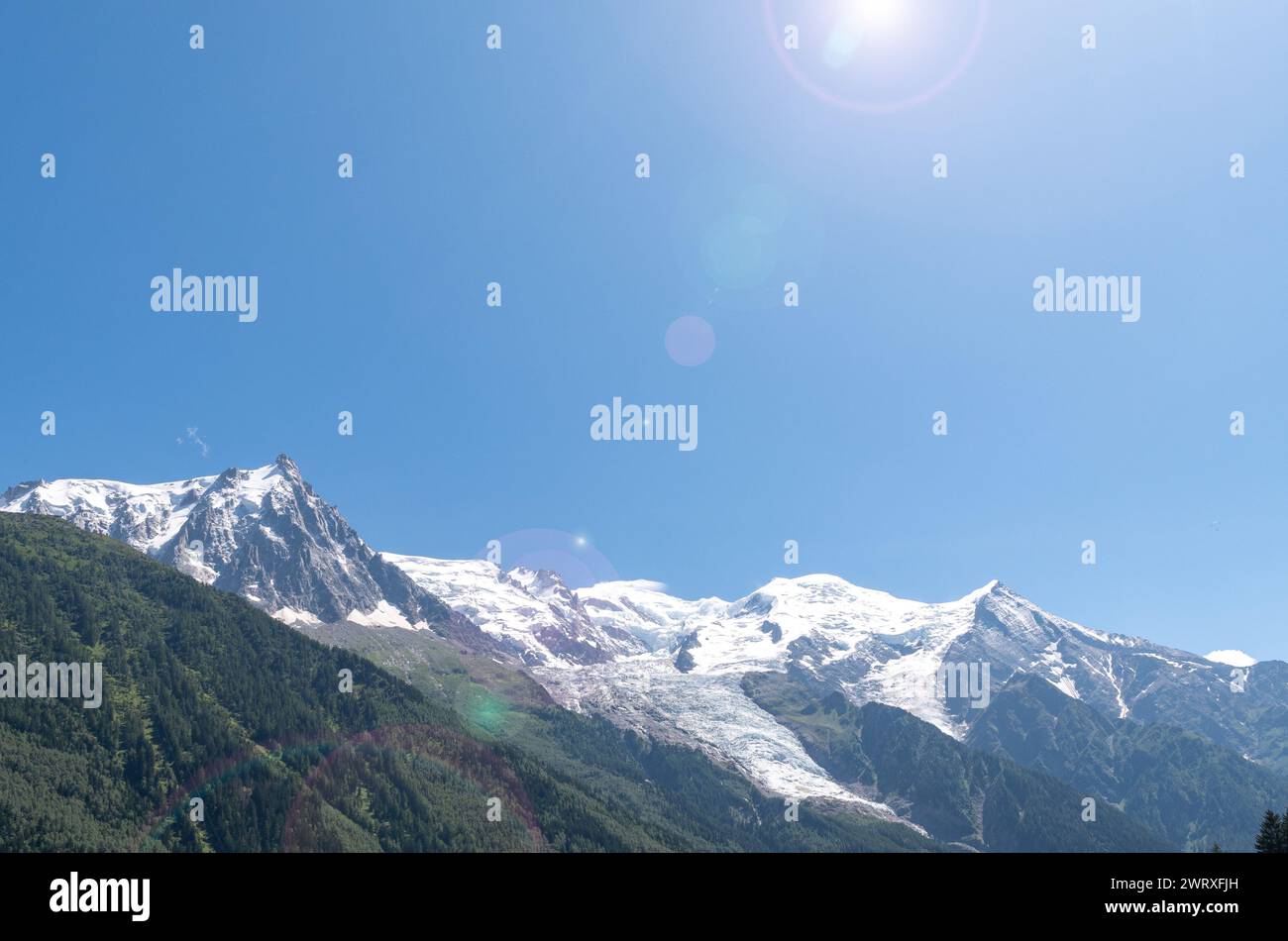 Vista retroilluminata con lenti svasate della cima del Monte bianco (4808 m), la montagna più alta delle Alpi, contro il cielo blu in estate, Chamonix, Francia Foto Stock