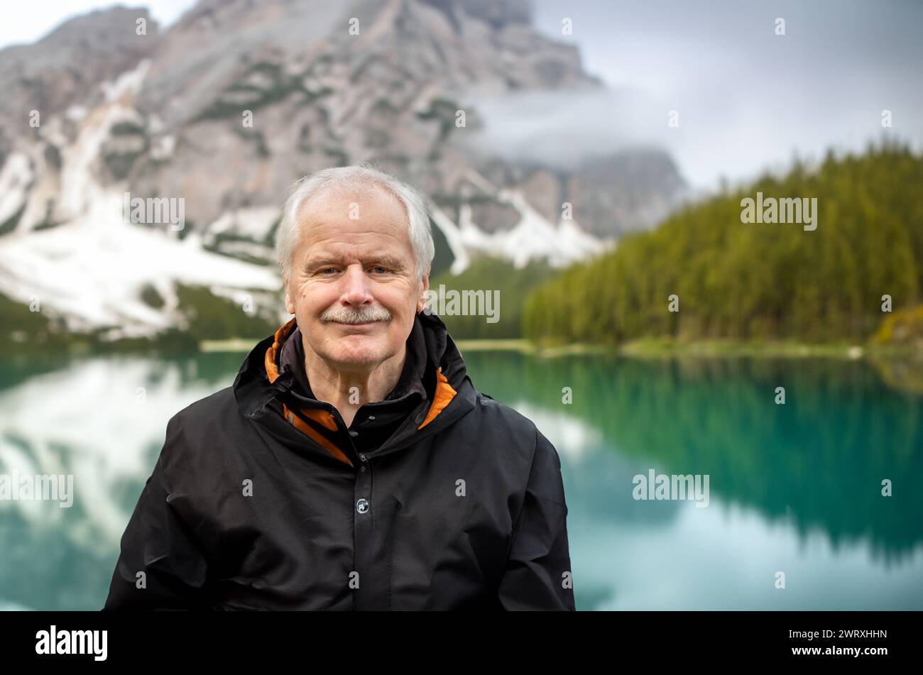 Uomo anziano in piedi da solo nel bel lago di montagna. Simbolo per rimanere attivi in età avanzata. Foto Stock