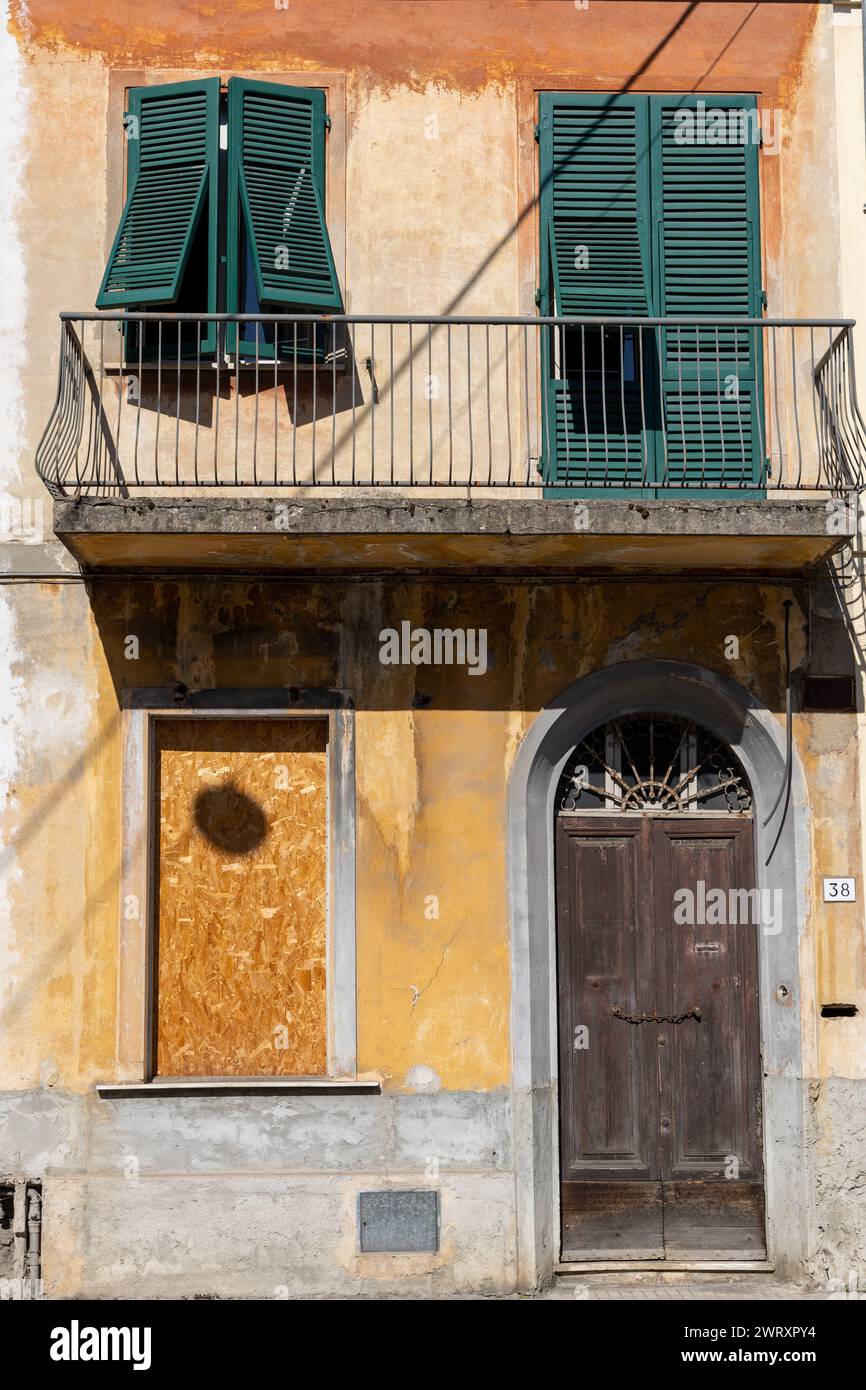 L'esterno e l'ingresso della casa a Pisa, Italia. Condizione di abbandono con intonaco che fuoriesce e si è abbattuto sul finestrino Foto Stock