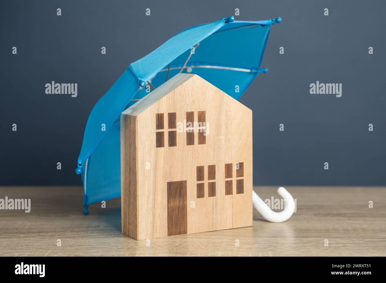Casa con ombrello blu. Assicurazione immobiliare. Sicurezza finanziaria. Proteggete gli investimenti e preparatevi a eventi imprevisti. Riparazioni o ricostruzioni in t Foto Stock