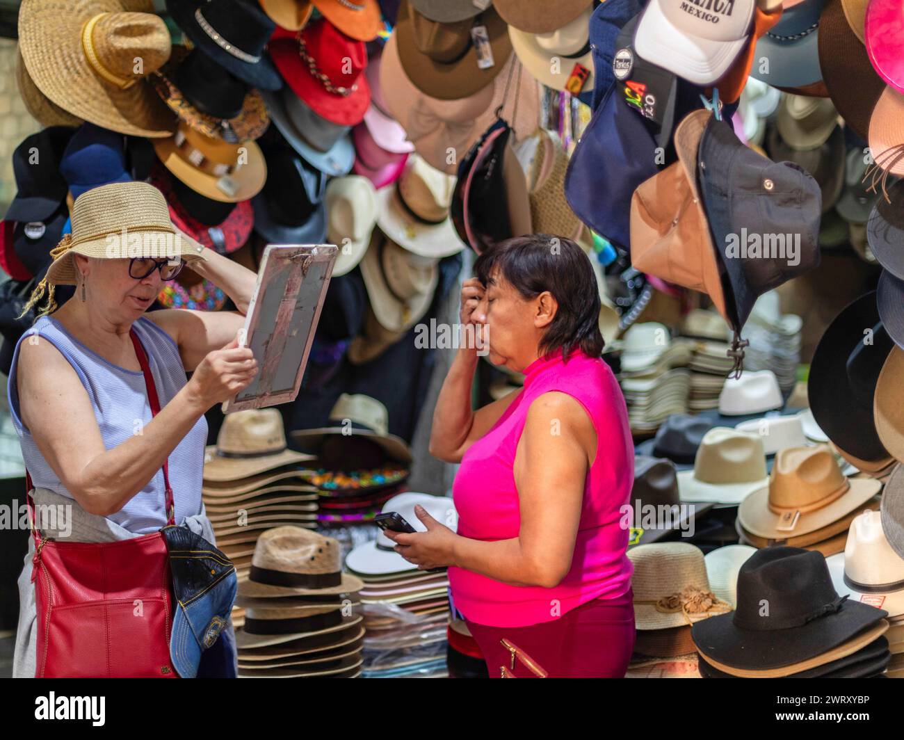 Oaxaca, Messico - Una donna vende un cappello a un turista al mercato Benito Juarez. Aperto nel 1894, è uno dei mercati più grandi e antichi di Oaxaca. Foto Stock