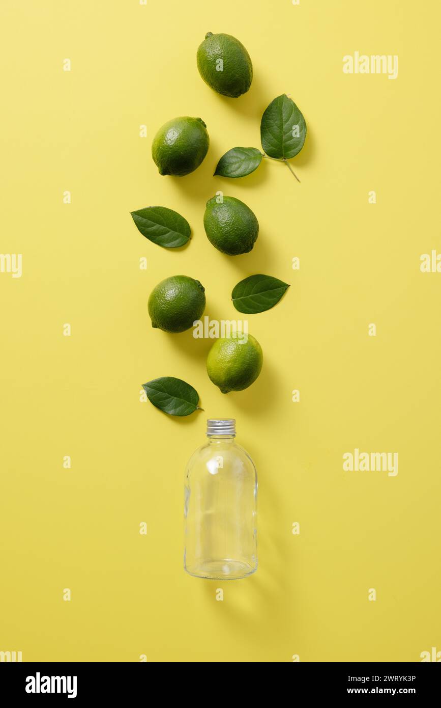 Foglie di limone e verde su una bottiglia di vetro trasparente Foto Stock