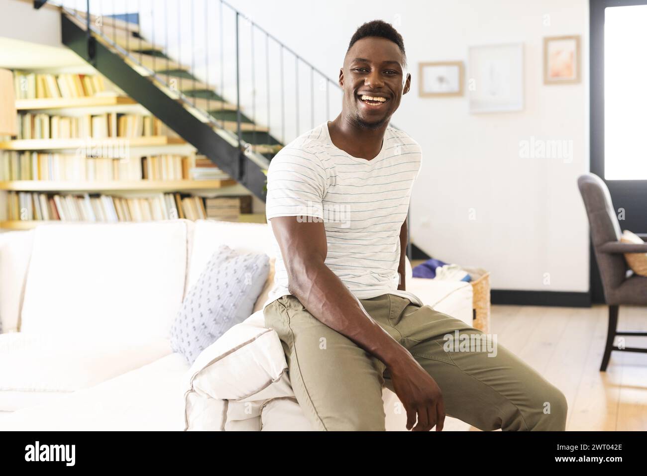 Un giovane afroamericano è seduto e brilla di gioia a casa Foto Stock