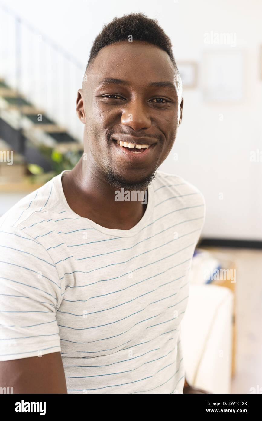 Un giovane afro-americano si irradia con un sorriso gioioso a casa Foto Stock