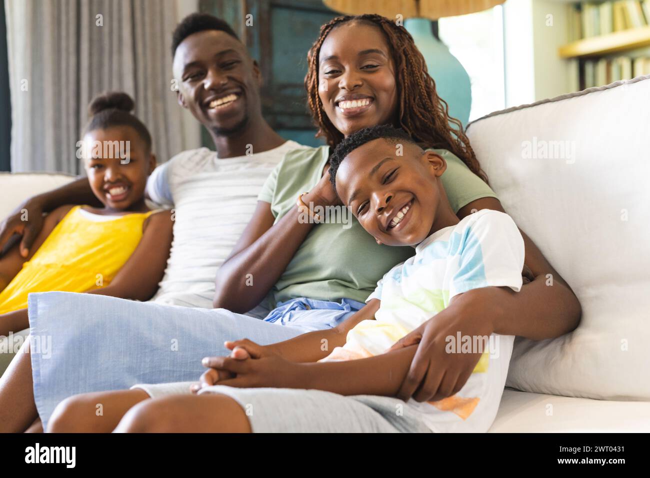 Una giovane famiglia afroamericana si rilassa insieme su un divano a casa Foto Stock
