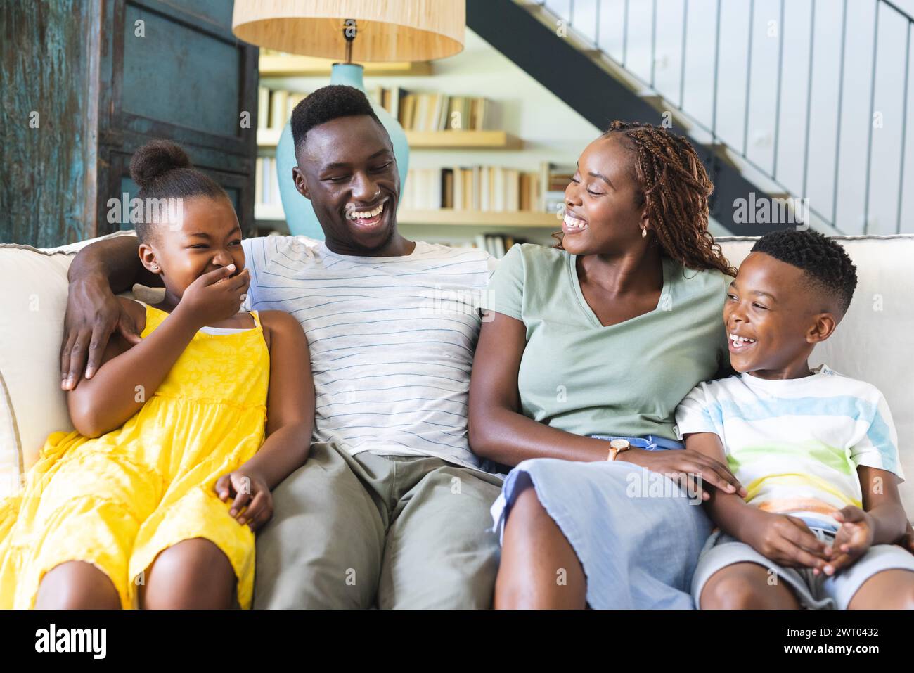 Una gioiosa famiglia afroamericana sta condividendo una risata insieme a casa sul divano Foto Stock