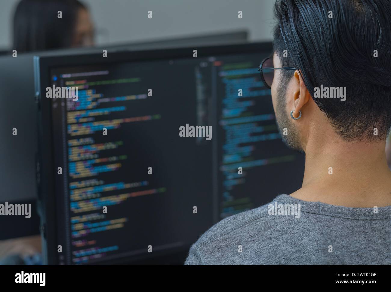 App asiatica di codifica per sviluppatori di ingegneri tempestivi con dati software posizionati di fronte al monitor del computer in ufficio Foto Stock