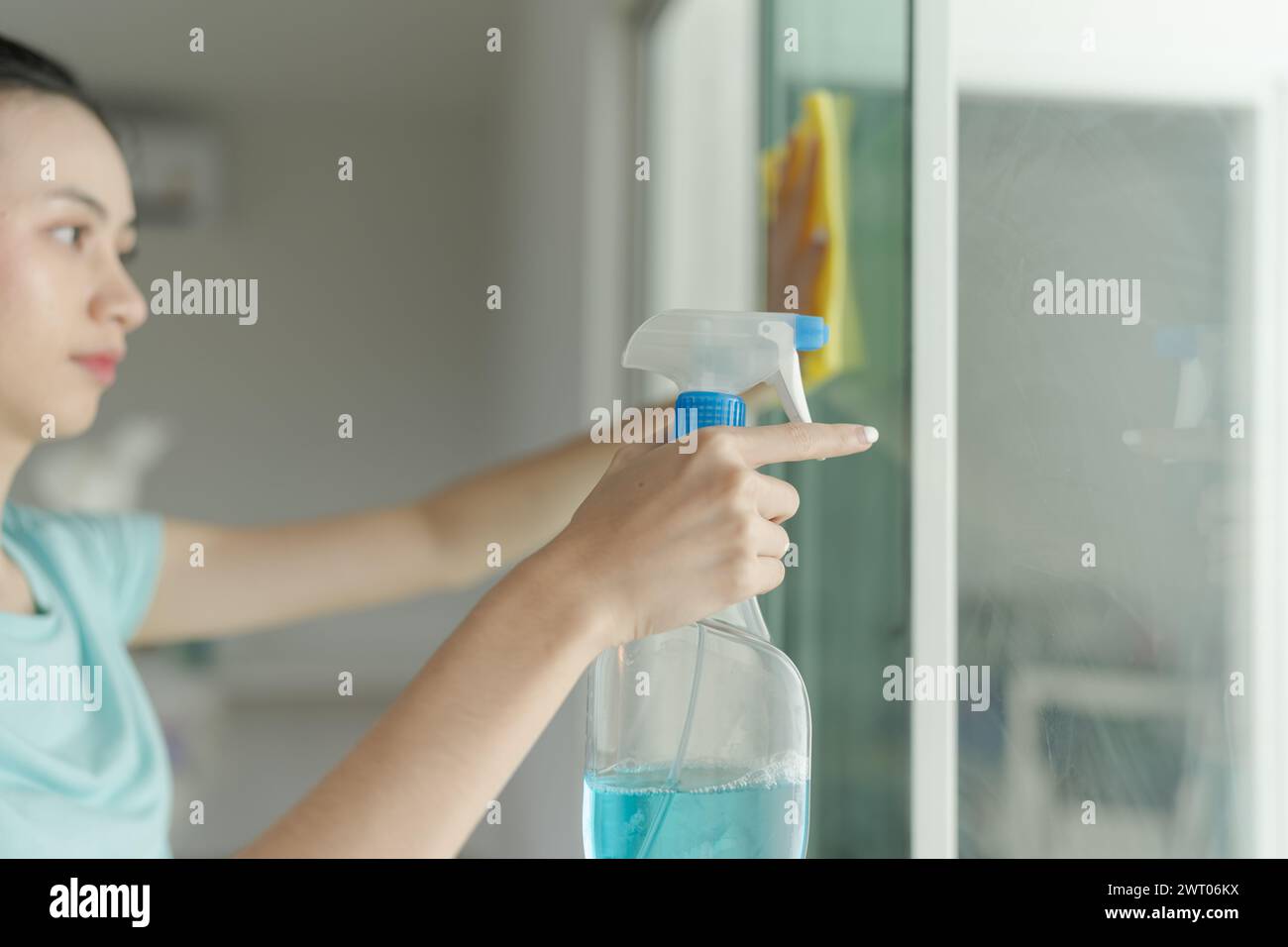 Bella donna che pulisce lo specchio della casa. Foto Stock