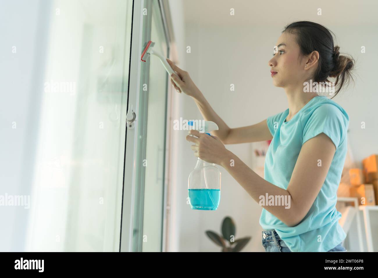 Bella donna che pulisce lo specchio della casa. Foto Stock