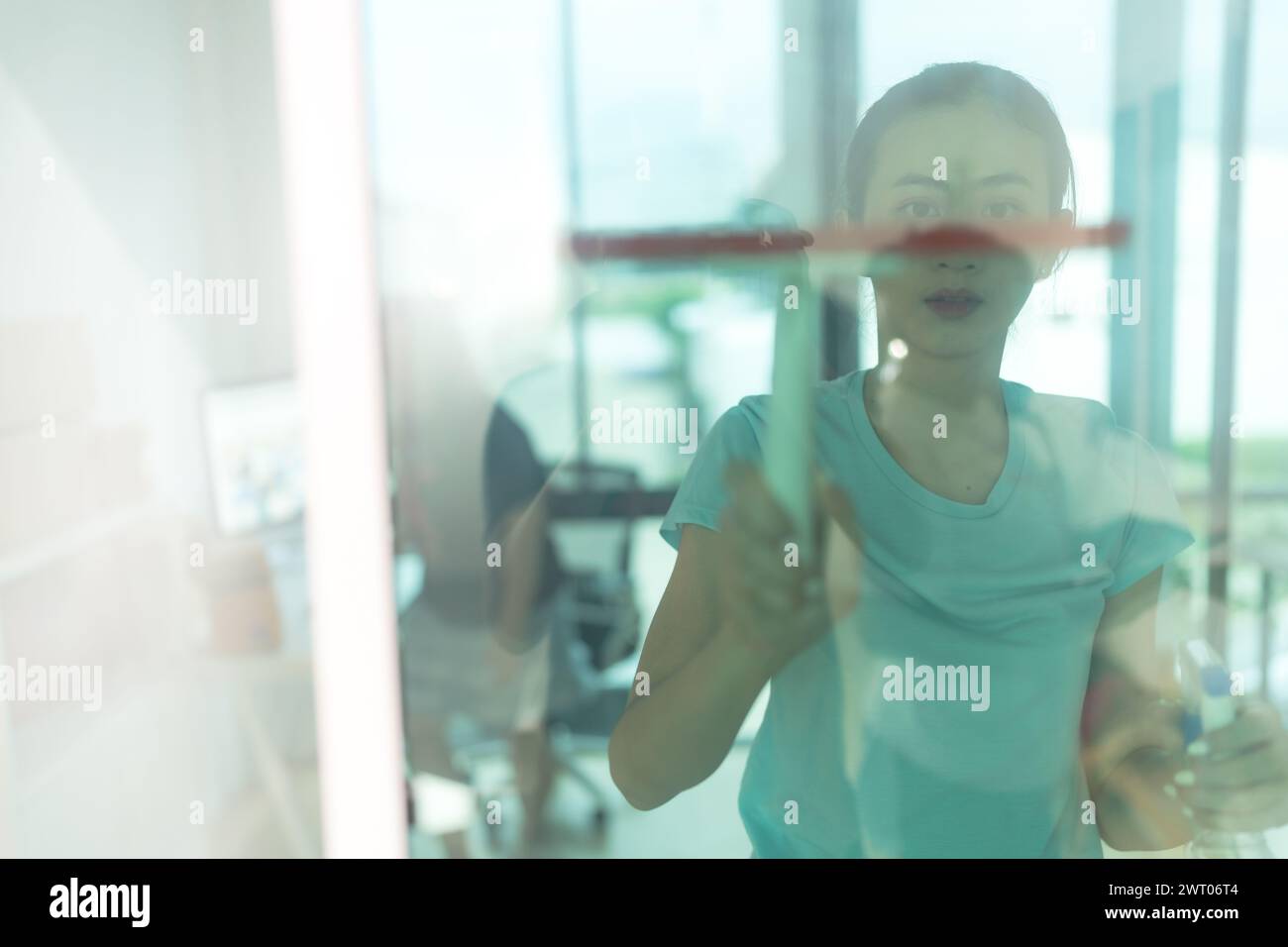 Bella donna che pulisce lo specchio della casa. Foto Stock