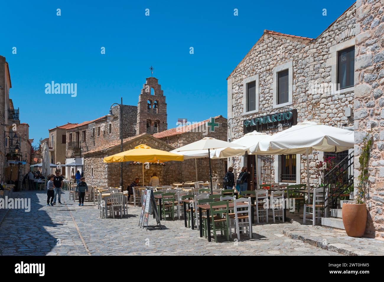 Strada soleggiata in una città vecchia con servizio catering all'aperto ed edifici tradizionali, città vecchia, Areopoli, Areopolis, Tsimova, Itylo, Anatoliki mani, mani Foto Stock