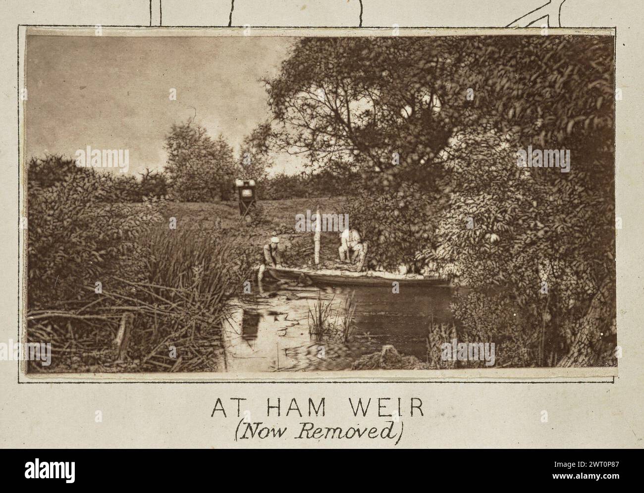 A Ham Weir (ora rimosso). Henry W. Taunt, fotografo (britannico, 1842 - 1922) intorno al 1886 una delle tre fotografie che illustrano una mappa stampata del castello di Eaton, Kempsford e dell'area circostante lungo il Tamigi. La fotografia mostra una vista di Henry taunt accovacciato sulla riva del fiume in una piccola diga. Tunt tiene la prua di una canoa che galleggia sull'acqua mentre un secondo uomo si accova vicino a lui sulla riva del fiume. La tenda fotografica di Tunt si trova in un campo dietro gli uomini. (Recto, monta) centro inferiore, sotto l'immagine, stampato con inchiostro nero: "AT HAM WEIR / (Now removed) [corsivo Foto Stock