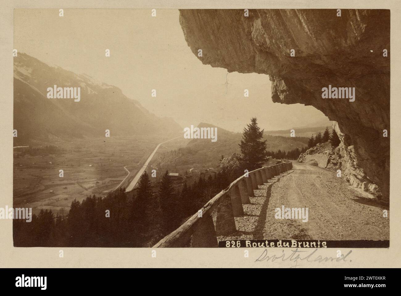 Route du Brunig. Sconosciuto, fotografo intorno al 1880-1890, Una strada di montagna che si snoda sotto il bordo sporgente di una formazione rocciosa. La strada è delimitata dalla montagna da un lato e da una recinzione di legno dall'altro. Il paesaggio circostante è ricoperto di alberi. (Recto, stampa) in basso a destra, inscritto in negativo: '826 Route du Brunig'; (Recto, Mount) centro a destra, sotto l'immagine, matita: 'Switzland. [sic]»; Foto Stock