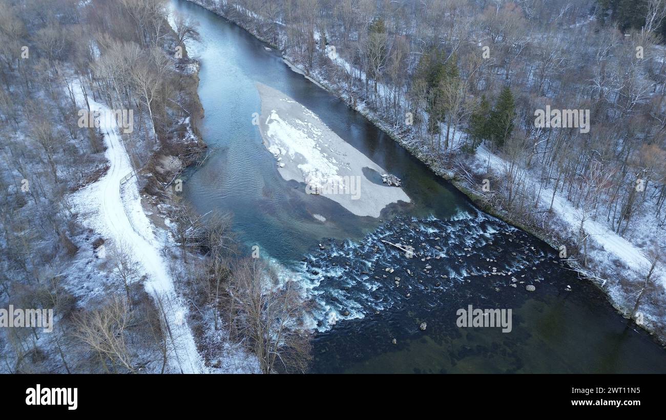 Il dolce abbraccio dell'inverno su un tranquillo fiume fiancheggiato da alberi spolverati di neve Foto Stock