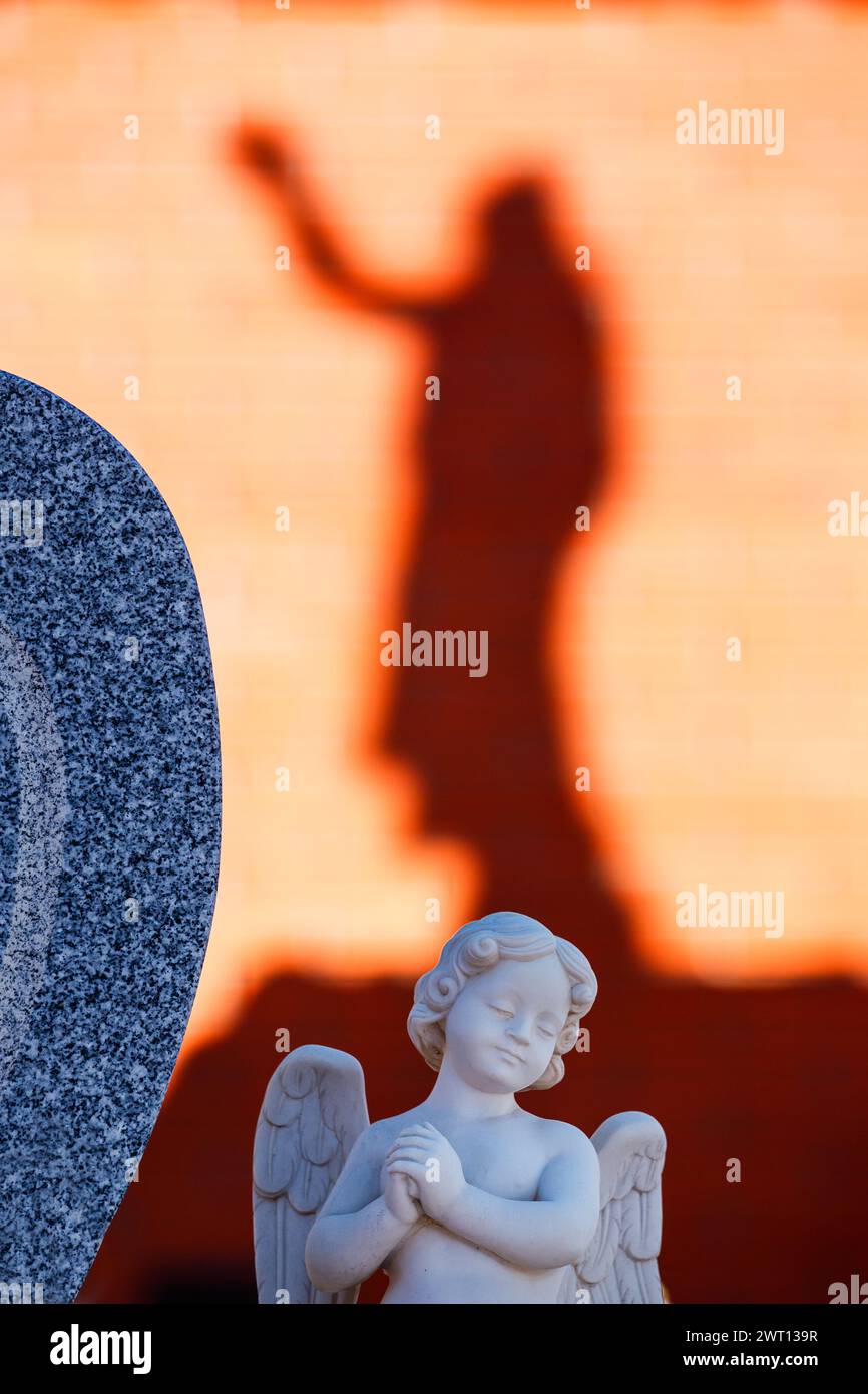 Statua di un angelo con l'ombra di Cristo sullo sfondo Foto Stock