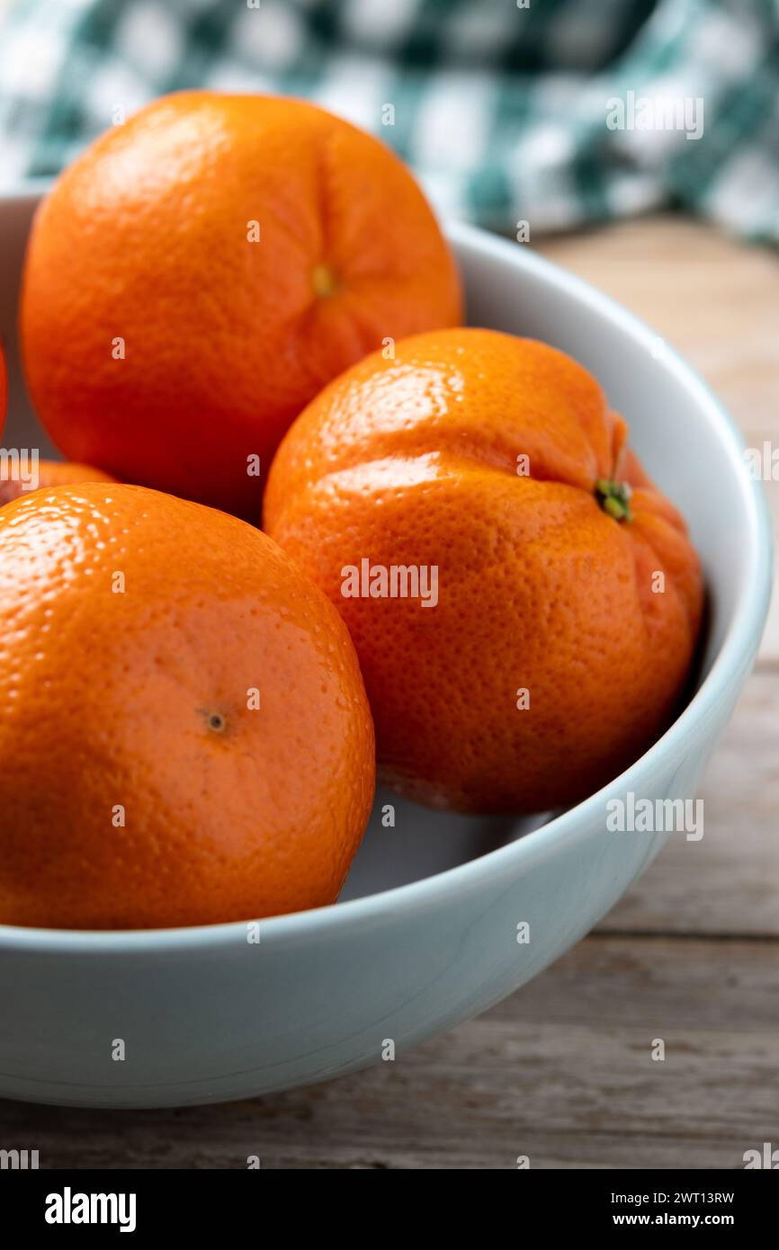Mandarini freschi nel recipiente su un tavolo di legno Foto Stock