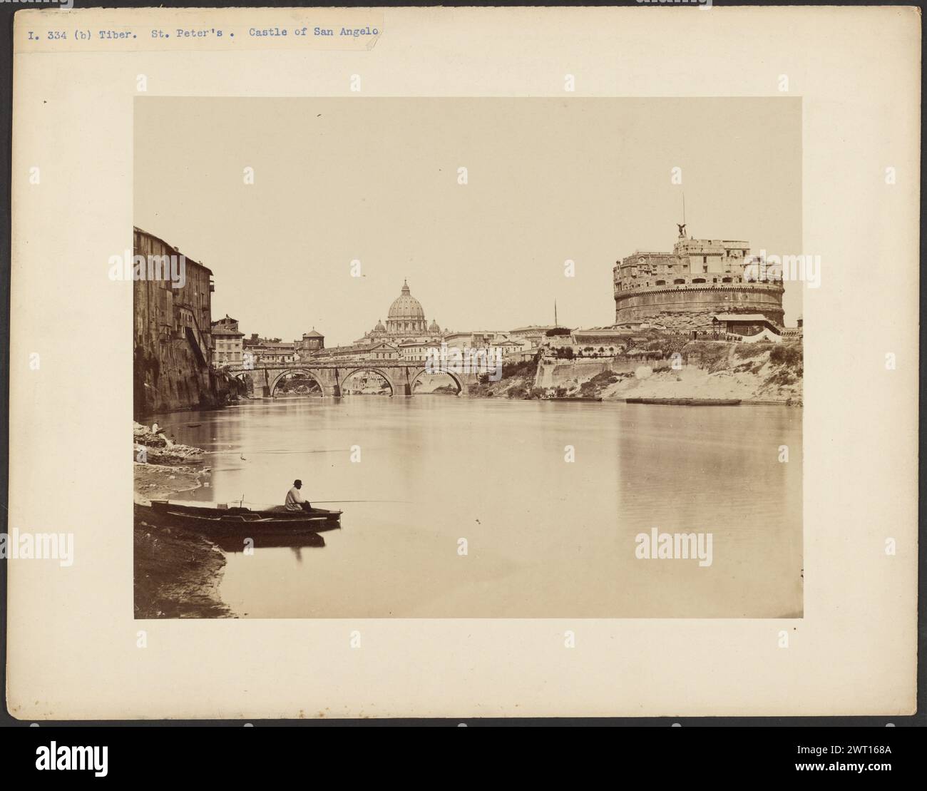 Castel Sant'Angelo veduto dal fiume con barchetta, Roma. Sconosciuto, fotografo circa 1880 Vista sul fiume Tevere con un edificio cilindrico sormontato da una statua di una figura alata sulla riva opposta. Il tetto a cupola di St. La Cattedrale di Pietro è visibile in lontananza. Un ponte ad arco attraversa il fiume di fronte alla cattedrale. Un uomo con una canna da pesca è seduto su una barca sulla riva vicina. (Recto, montaggio) in alto a sinistra, stampa blu su etichetta di carta: "I. 334 (b) Tevere. St. Peter Castello di San Angelo"; (verso, monte) centro, inciso nel negativo su carta allegata: '17 fuso Foto Stock
