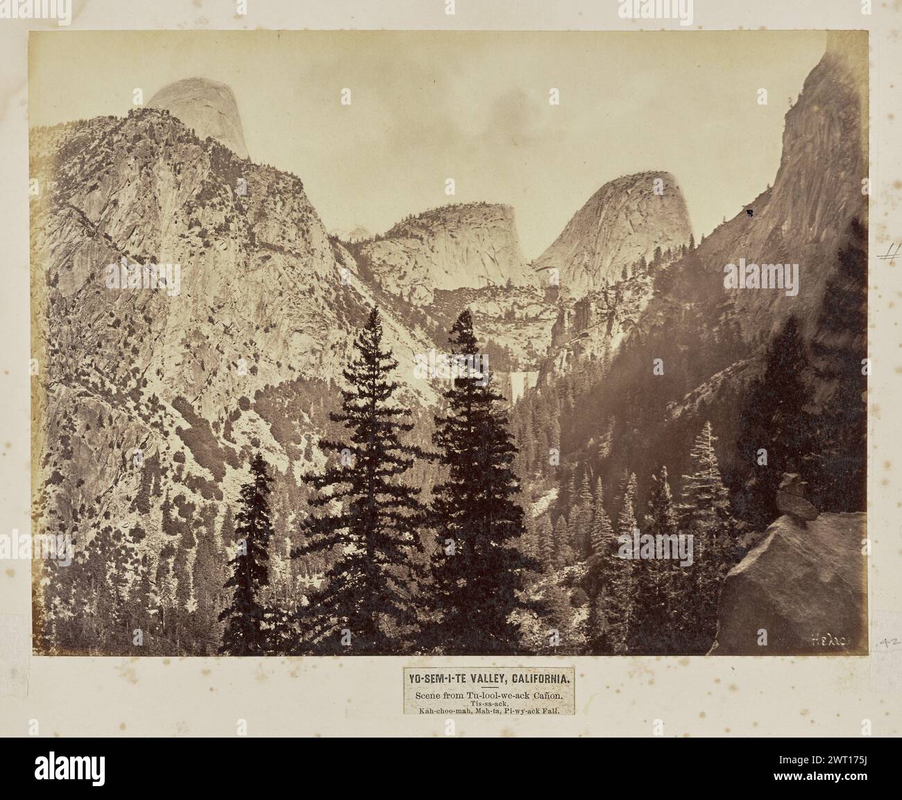 Yo-Sem-i-te Valley, California. Scena di tu-lool-we-ack Cañon. TIS-sa-ack, Kah-choo-mah, Mah-ta, Pi-wy-ack Fall. Eadweard J. Muybridge, fotografo (American, Born England, 1830 - 1904) negativo 1867, stampa Later View of a Scenarios in Yosemite National Park as seen from a distance. Il Monte Broderick e il Liberty Cap, conosciuti rispettivamente come 'Kachoomah' e 'Mahta' nella lingua Ahwahnechee nativa, possono essere visti come due formazioni rocciose adiacenti con cima curva al centro dell'immagine. Sotto di loro c'è Vernal Fall o 'Py-wy-ACK' Fall. Metà cupola o "Tis-sa-ack" è parzialmente visibile nell'area superiore sinistra Foto Stock
