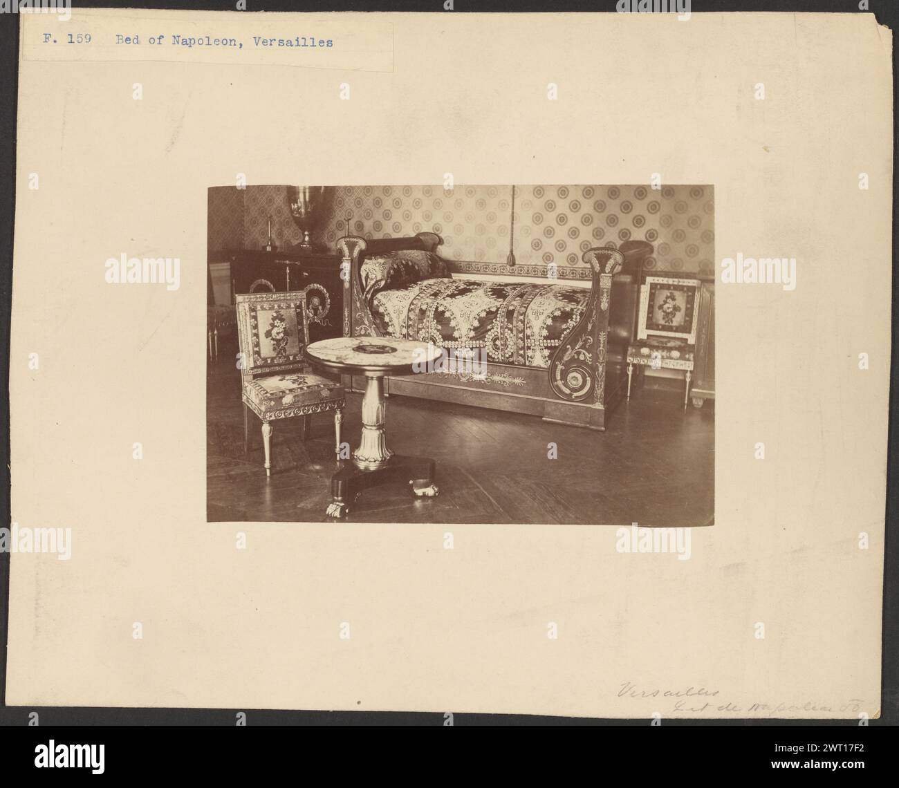 Letto di Napoleone i, Versailles. Sconosciuto, fotografo circa 1865–1875 Un piccolo letto con testata e pediera di uguale altezza. C'e' una sedia da pranzo imbottita accanto ad un piccolo tavolo a piedistallo davanti al letto. Una corda con una nappina è appesa al centro del letto. (Recto, Mount) in alto a sinistra, stampa blu su etichetta di carta: "F. 159 letto di Napoleone, Versailles"; in basso a destra, matita: "Versailles/lit de Napoleon [illeg]"; (verso, Mount) in basso a sinistra, matita: "E.B.W."; Foto Stock