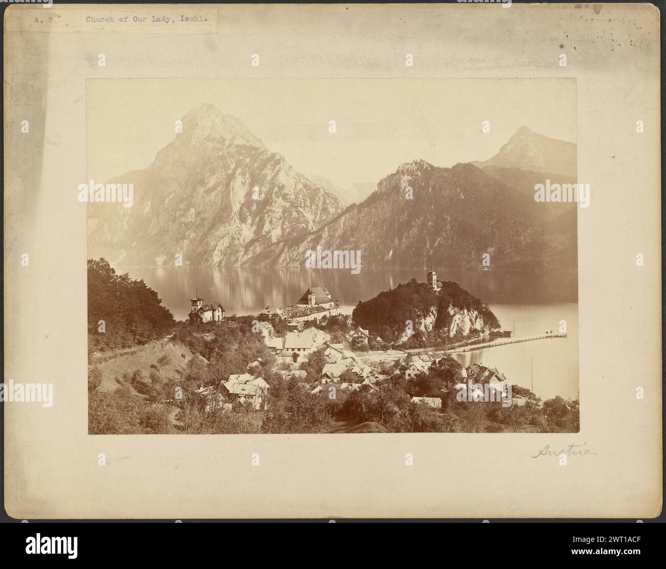 Chiesa di nostra Signora, Bad Ischl. Sconosciuto, fotografo intorno al 1870-1880 Vista di Traunkirchen, Austria, una città costruita lungo il bordo dell'acqua, sul fondo di una valle. La città è circondata da alte cime montuose. Un terreno rotondo si estende nell'acqua, coperto da colline e foreste. E' presente un unico edificio con una piccola torre in cima alla massa del terreno. (Recto, Mount) in basso a destra, matita: "Austria"; Foto Stock