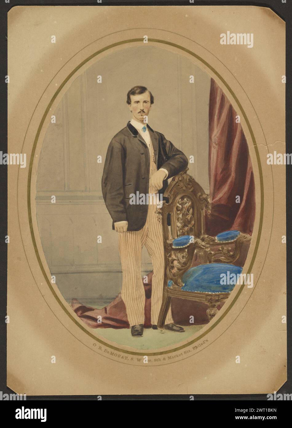 Ritratto di un uomo. Oliver Boudrias DeMorat, fotografo (americano, Born Canada, 1835 - 1902) fine anni '1850 Ritratto di un uomo in piedi con un gomito appoggiato su una sedia intagliata e imbottita, con una tenda su un lato. La giacca da uomo è nera, mentre la tenda è Bordeaux e i cuscini della sedia sono blu brillante. (Verso, Mount) in alto a destra, a matita: "GE/2761/ 7 1/2" x 5 1/2"/ MONTATO"; al centro, a matita: "8743"; Foto Stock