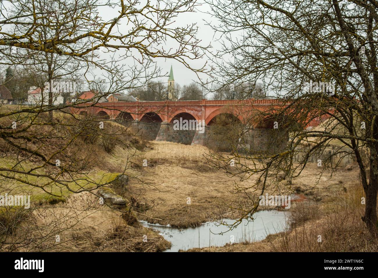 Nel cuore di Kuldiga, il ponte in mattoni rossi è una silenziosa testimonianza dell'evoluzione della città, una testimonianza del suo spirito duraturo. Foto Stock