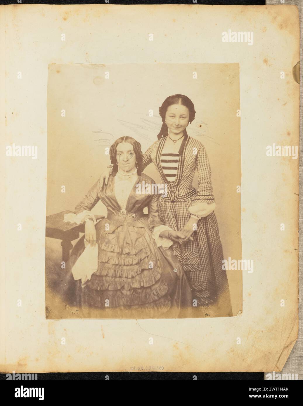 Ritratto di due donne che si tengono per mano. Jakob Höflinger, fotografo (svizzero, 1819 - 1898) circa 1853-1860, Un ritratto di due giovani donne che si tengono per mano. Uno indossa un vestito con volant e si siede con un braccio appoggiato su un tavolino. La seconda donna indossa un abito a scacchi con corpetto a righe. E' accanto all'altra donna. Foto Stock