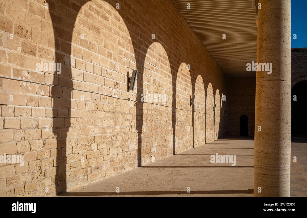 Le ombre dei tradizionali archi islamici a ferro di cavallo lungo il lato del sahn, o cortile, nella grande Moschea di Mahdia, Tunisia. Foto Stock