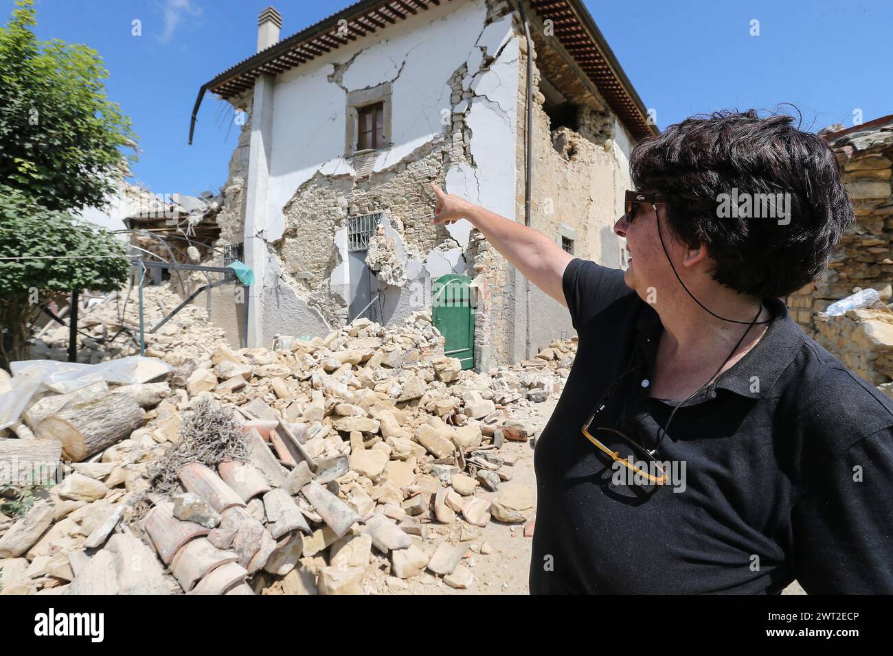 Una donna indica il luogo in cui si trovava la sua casa, completamente crollata dopo il terremoto che ha colpito la città di Amatrice, nel centro Italia. Foto Stock