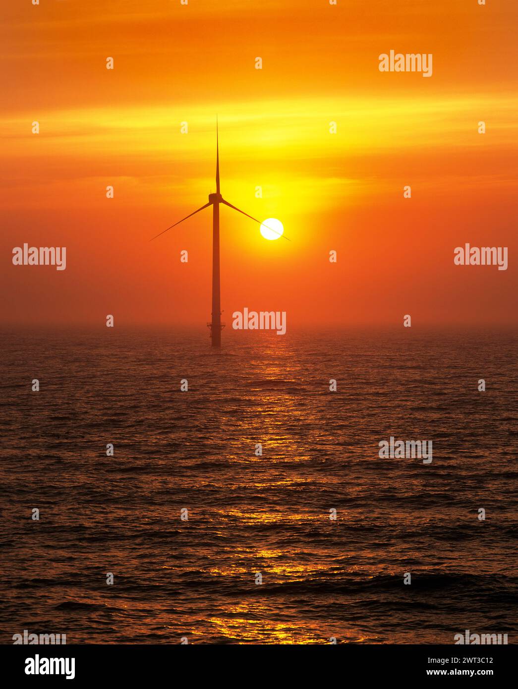 Il sole sorge dietro una delle turbine eoliche del primo parco eolico offshore britannico vicino a Blyth, Northumberland. Foto Stock