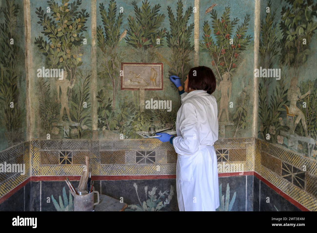 Un restauratore lavora su uno degli affreschi della restaurata Orchard House, situata negli scavi archeologici di Pompei. Foto Stock
