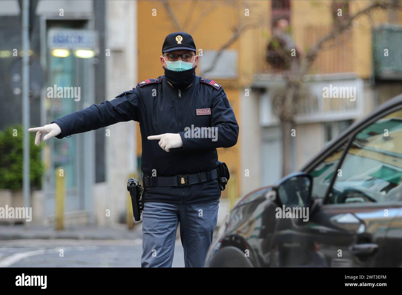 Un poliziotto ad un checkpoint, con una maschera per proteggersi, durante un controllo per verificare i movimenti di persone per le limitazioni di Coronavirus COVID Foto Stock