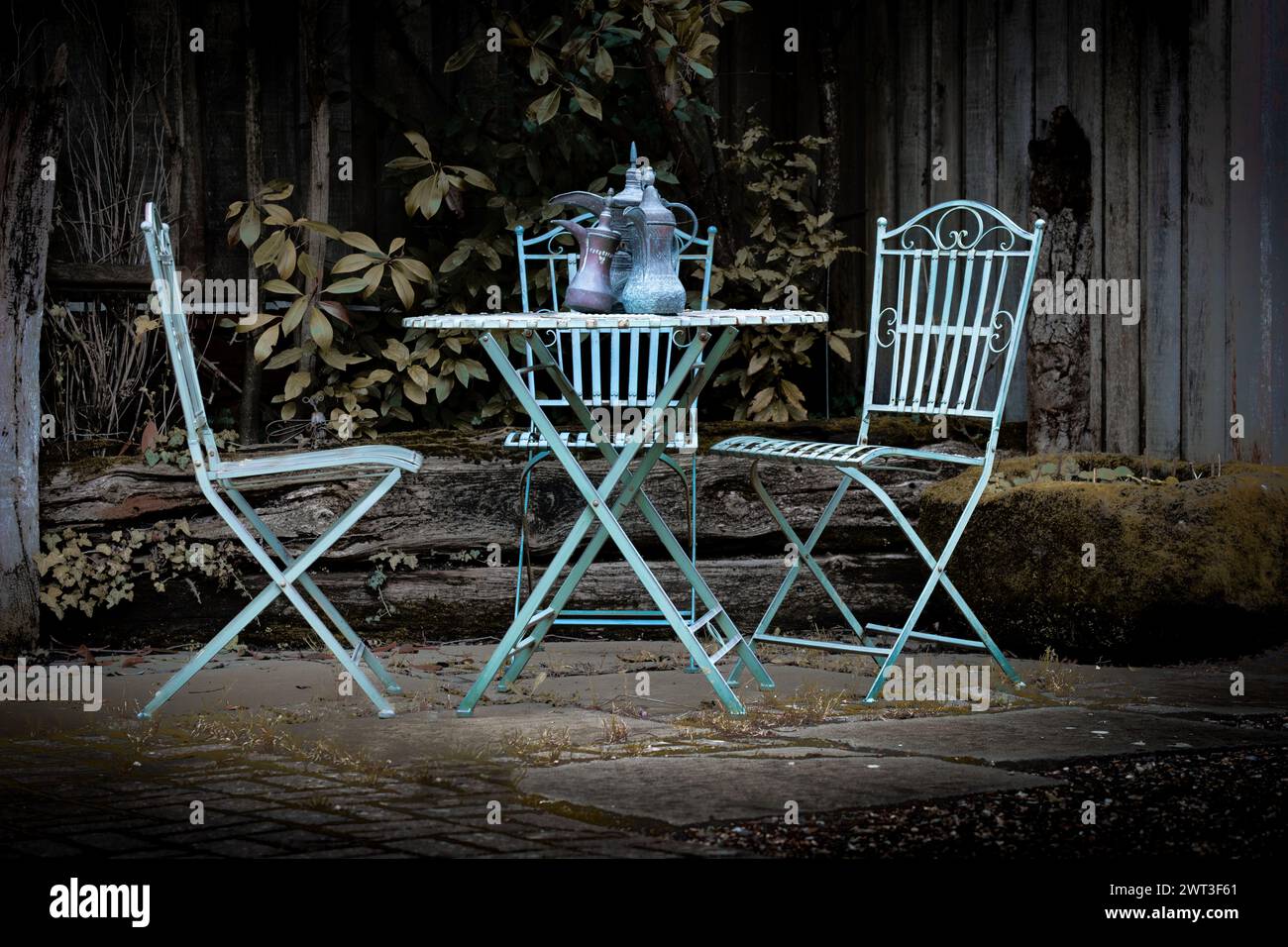 Tavolo in ferro rustico e sedia da giardino in stile cottage giardino con brocche in metallo di stile mediorientale Foto Stock