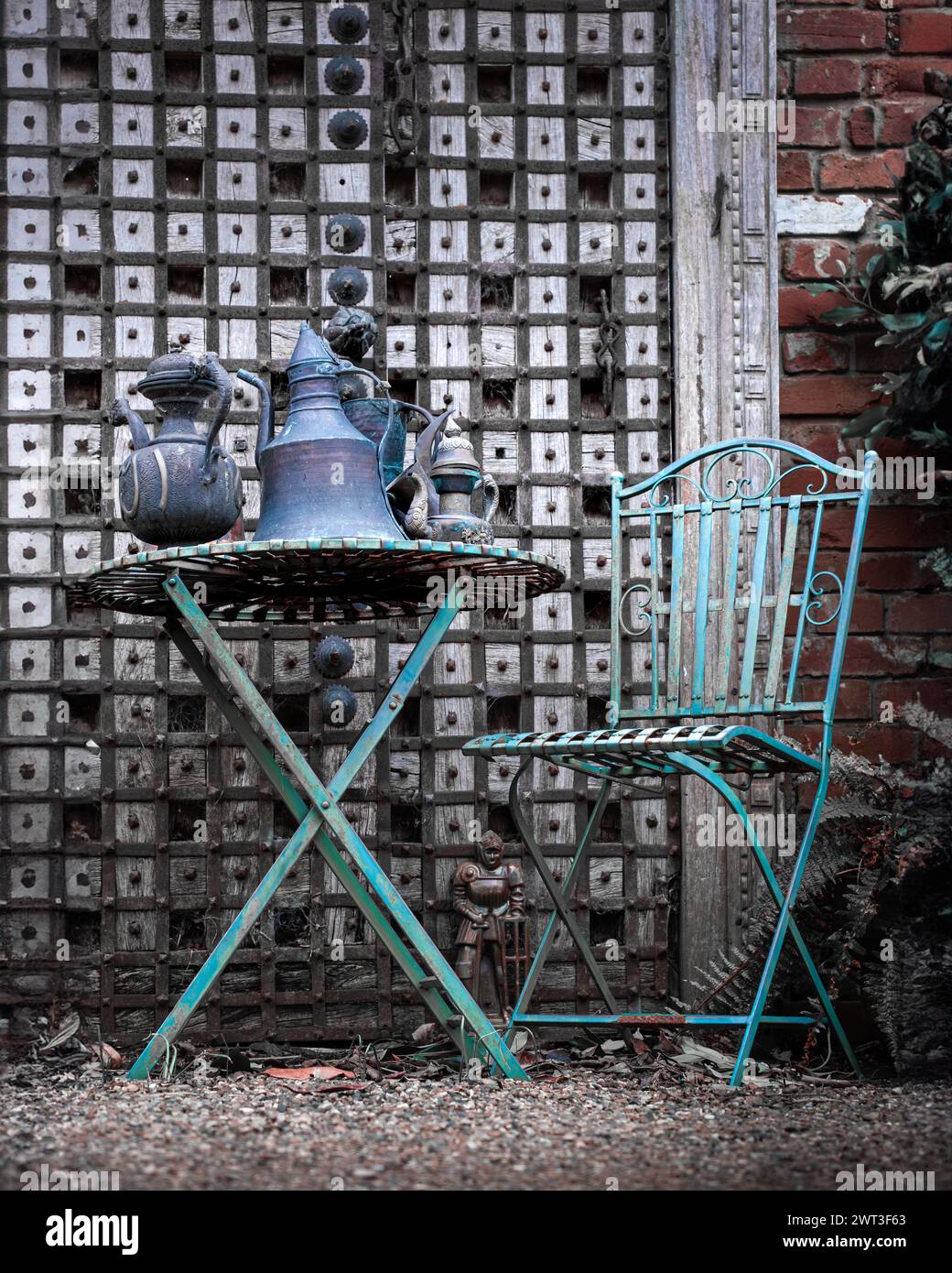 Tavolo in ferro rustico e sedia da giardino in stile cottage giardino con brocche in metallo di stile mediorientale Foto Stock