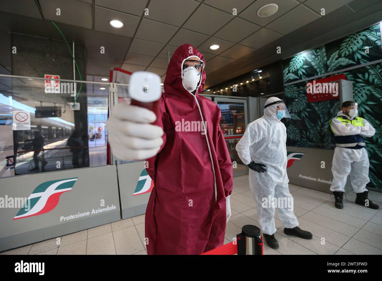 Un uomo della protezione civile italiana, punta uno scanner termico, nella stazione ferroviaria di Napoli, per controllare le persone dopo l'allentamento della restrittiva mea Foto Stock